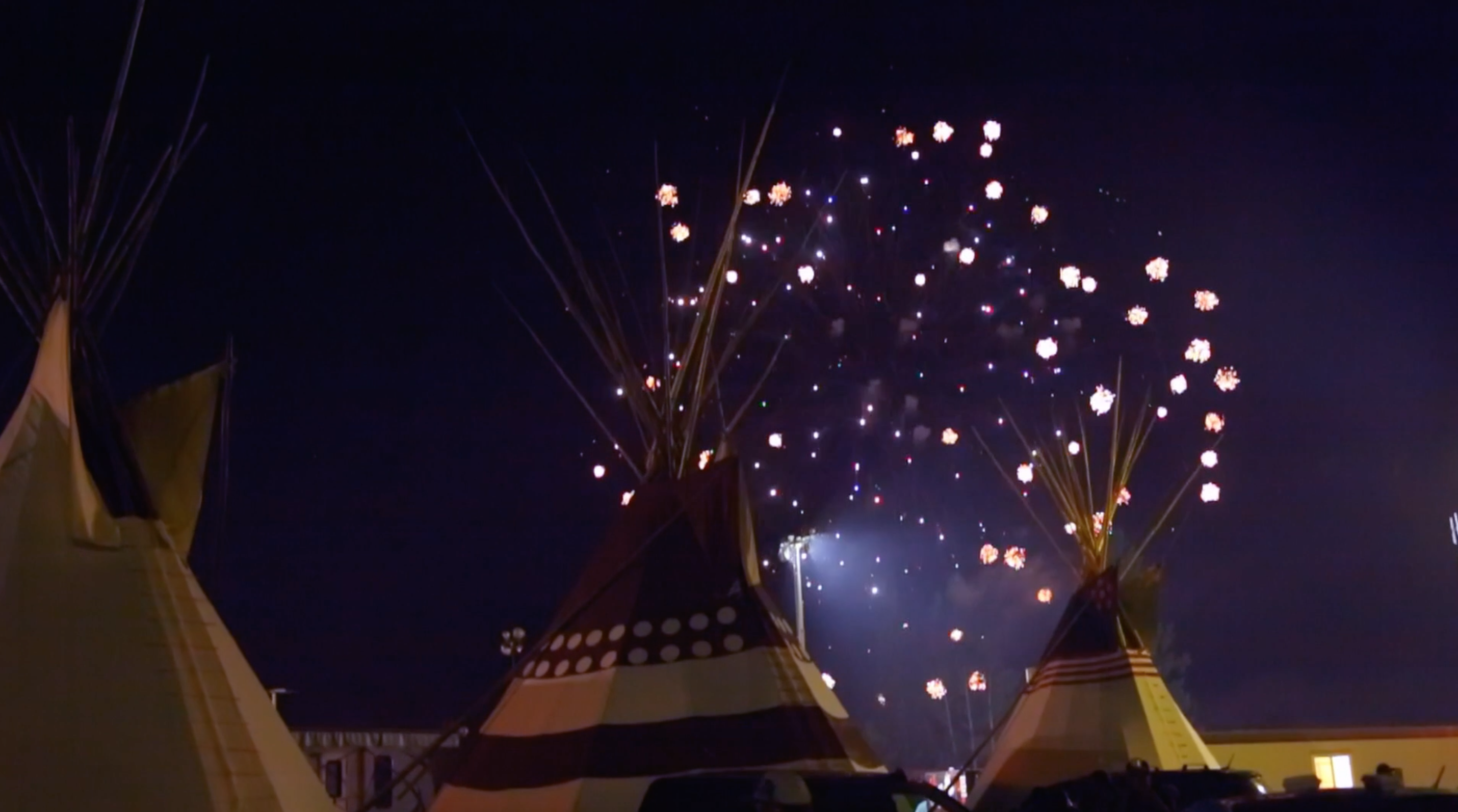 Fireworks going off in the night over teepees