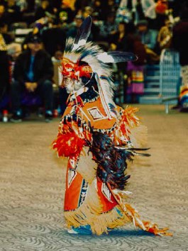 Native American boy dressed in traditional clothing performing a dance